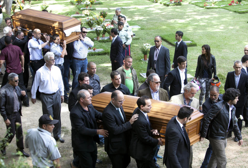 Relatives and friends carry the remains of Monica Spear, right, and of her ex-husband Thomas Henry Berry, top left, during their funeral at the East Cemetery in Caracas, Venezuela, Friday, Jan. 10, 2014. Robbers killed actress Spear, 29, and her former husband Berry, 39, late Monday night on an isolated stretch of highway while the couple was returning to the capital by car with their 5-year-old daughter from a vacation. (AP Photo/Alejandro Cegarra)