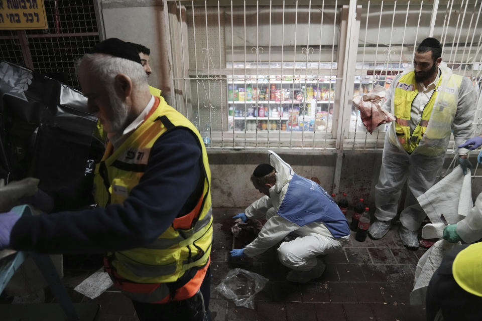 Israeli Zaka Rescue and Recovery team cleans blood from the site where a gunman opened fire in Bnei Brak, Israel, Tuesday, March 29, 2022. A gunman on a motorcycle opened fire in central Israel late Tuesday, in the second fatal mass shooting rampage this week. The shooter was killed by police. (AP PhotoOded Balilty)