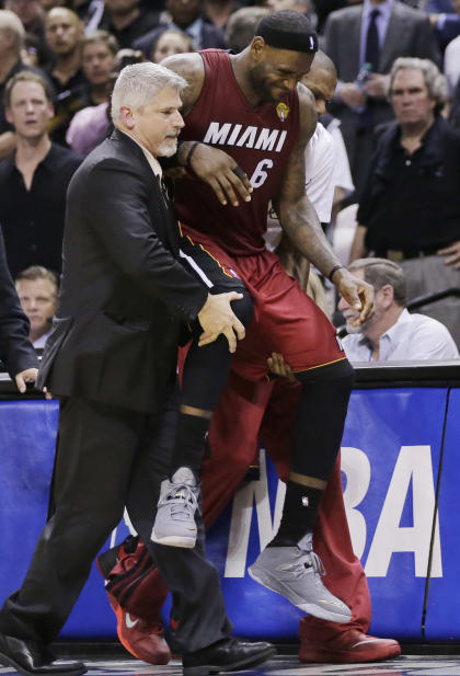 LeBron James needs help to get to the bench in the fourth quarter of Thursday's NBA Finals opener. (AP) 