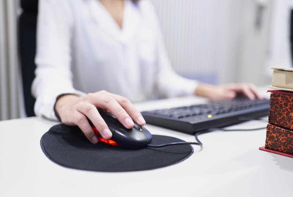 Middle view human hand using mouse on mouse pad at the office desktop next to keyboard