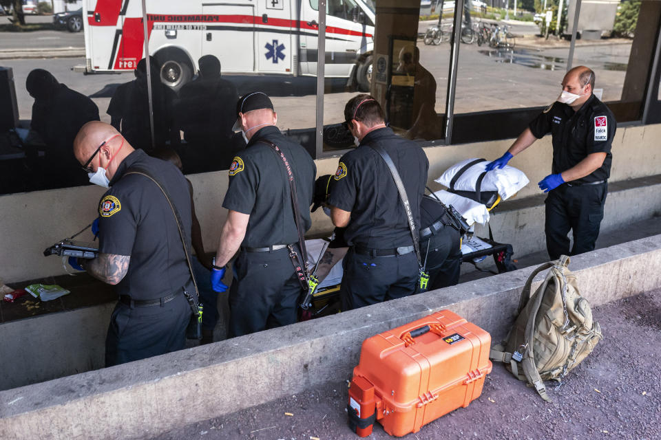 Salem Fire Department paramedics and employees of Falck Northwest ambulance service respond to a heat exposure call during a heat wave, Saturday, June 26, 2021, in Salem, Ore. (AP Photo/Nathan Howard)