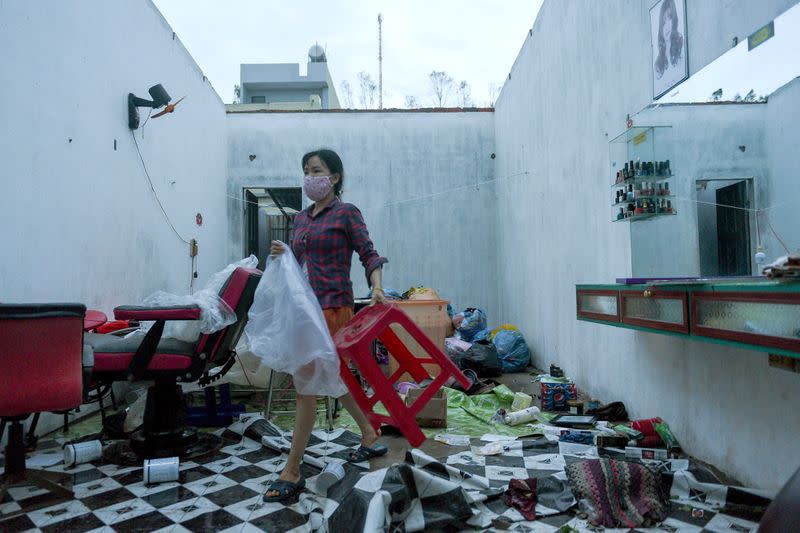 A woman works in a barbershop damaged by the Typhoon Molave in Binh Chau village