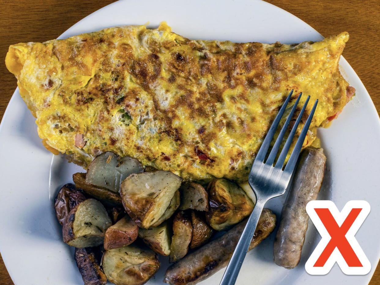 omelet with breakfast potatoes and a fork on a white plate