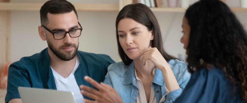 Focused young family couple listening to African-American mortgage lender.