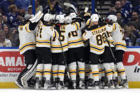 Boston Bruins players mob center Patrice Bergeron after Bergeron assisted on a goal by left wing Brad Marchand for his 1,000th career point against the Tampa Bay Lightning during the second period of an NHL hockey game Monday, Nov. 21, 2022, in Tampa, Fla. (AP Photo/Chris O'Meara)