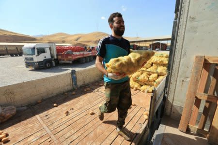 A worker carries a bag of potatoes from the truck coming from Turkey, in the town of Zakho, Iraq October 11, 2017.  REUTERS/Ari Jalal