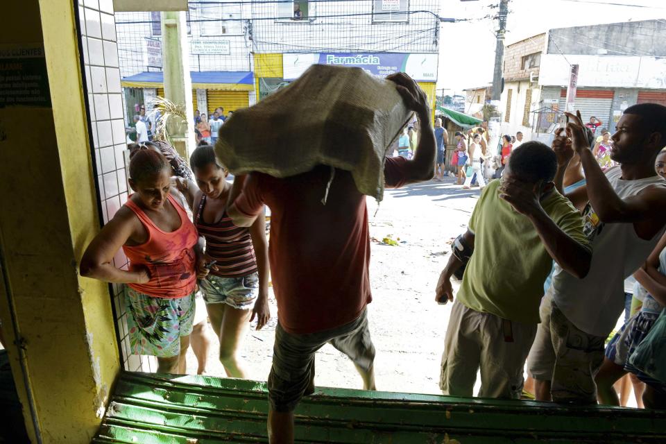 A man carries goods out of a supermarket that was looted during a police strike in Salvador