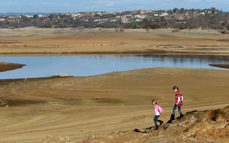 Children walk on rocks that are normally on the shore of Folsom Lake, California., a reservoir that at the time had receded more than 100 yards. - Credit: Rich Pedroncelli/AP