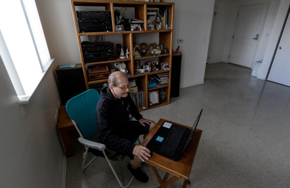 Henry Argueta sits at his computer in his apartment.