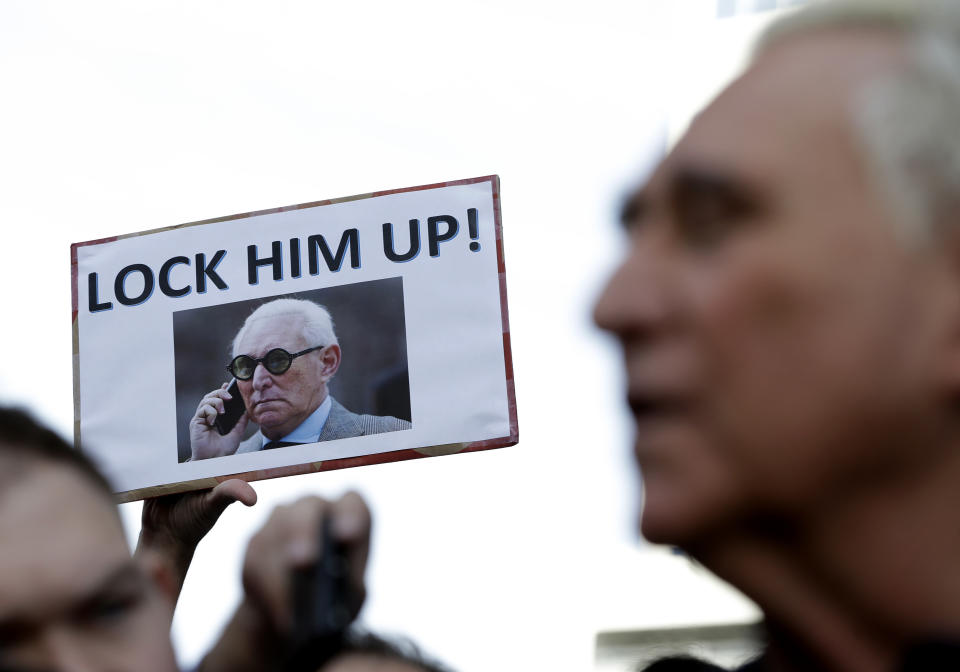 A protester holds up a sign as Roger Stone, right, a confidant of President Donald Trump, speaks outside of the federal courthouse following a hearing, Friday, Jan. 25, 2019, in Fort Lauderdale, Fla. Stone was arrested Friday in the special counsel's Russia investigation and was charged with lying to Congress and obstructing the probe. (AP Photo/Lynne Sladky)