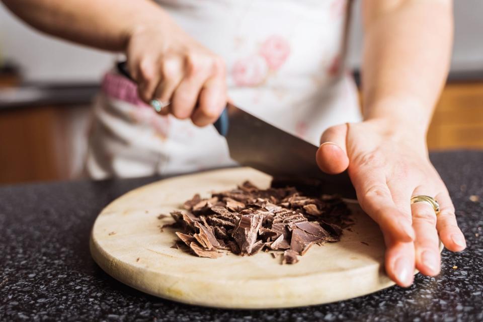 woman chopping chocolate on wood cutting board
