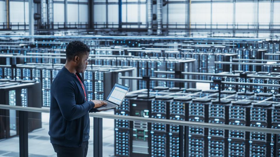 A man examining servers in a data center.