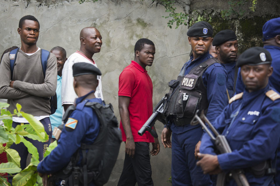 Congolese voters wake past police as they reach the St. Raphael school in the Limete district of Kinshasa Sunday Dec. 30, 2018 to cast their ballot. Forty million voters are registered for a presidential race plagued by years of delay and persistent rumors of lack of preparation. (AP Photo/Jerome Delay)