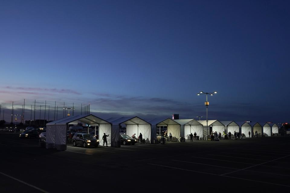 Several tents are set up so people who have registered can get their COVID-19 vaccinations as they drive-thru the parking lot of the State Farm Stadium, Tuesday, Jan. 12, 2021, in Glendale, Ariz. The Arizona Cardinals' stadium opened as a vaccination site Monday that will be a 24-7 operation. (AP Photo/Ross D. Franklin)