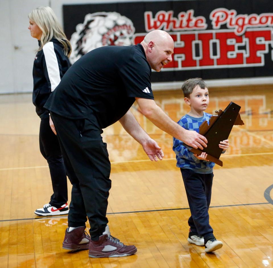 Brandywine coach Nathan Knapp, left, hands the district championship trophy to his grandson, Kenzo, to hand to the team following the MHSAA Division 3, District 79 championship game Friday, March 1, 2024, at White Pigeon High School.