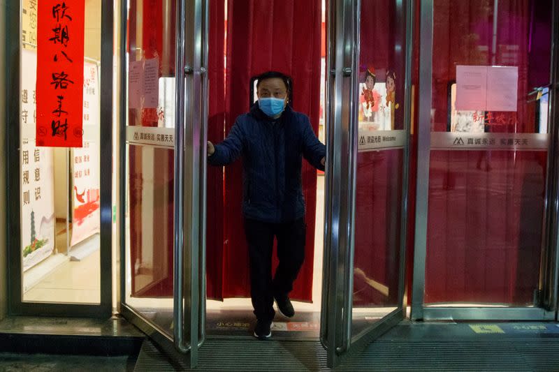 A man wearing a face mask closes a supermarket in Jiujiang