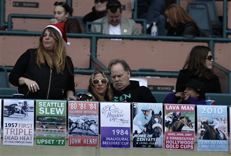 Horse racing fans display historical posters at Betfair Hollywood Park, which is closing down at the conclusion of tomorrow's race card after operating for 75 years, in Inglewood, California December 21, 2013. REUTERS/Jonathan Alcorn