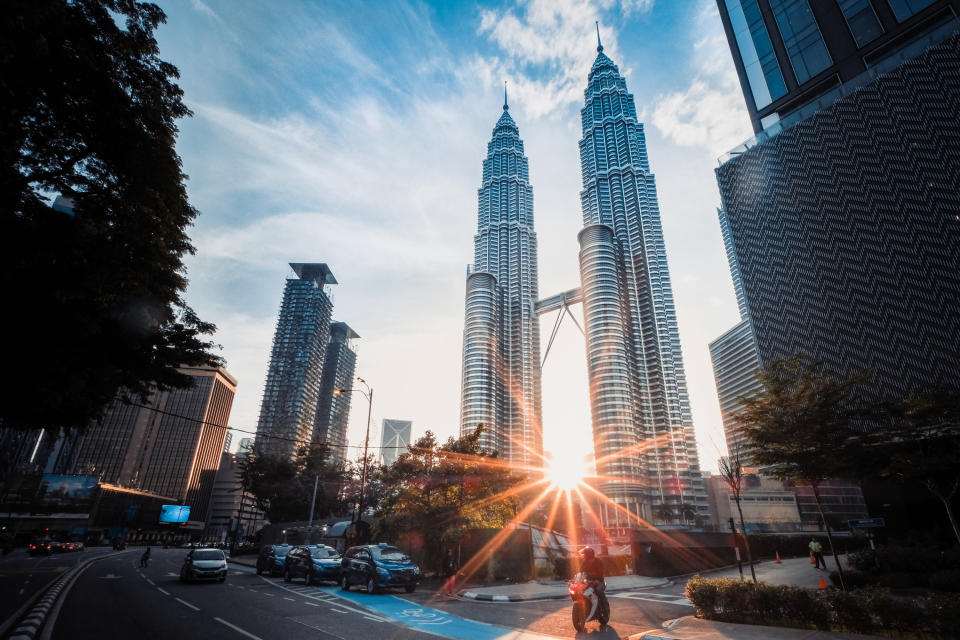 Two very tall, tiered buildings with antenna spires and a walkway between them