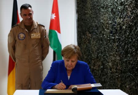 German Chancellor Angela Merkel writes in a book as she visits German soldiers stationed in Jordan, June 21, 2018. REUTERS/Muhammad Hamed