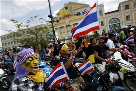 An anti-government protester, wearing a mask, gathers with other protesters with Thai national flags outside the Defense Ministry in central Bangkok November 28, 2013. REUTERS/Damir Sagolj