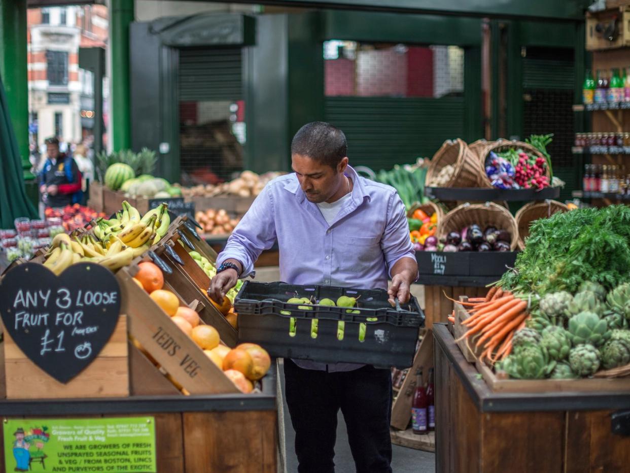 A man places fruit and vegetables on display at a stall in Borough Market on July 3, 2017 in London, England. On 3 June 2017, Islamist terrorists attacked people with knives in the market after ploughing their van into pedestrians on London Bridge. In total, 8 people were killed and 48 were injured, the attackers were all shot dead by police. (Photo by )