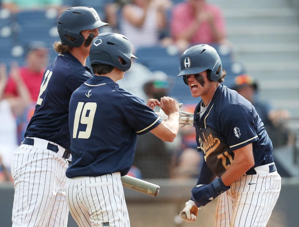 Archbishop Hoban Andrew Karhoff joins Colin Coyne as they celebrate at home plate with Zack Zimmerman after Coyne and Zimmerman scored against Badin in a Division II state semifinal game at Canal Park on June 10, 2022.