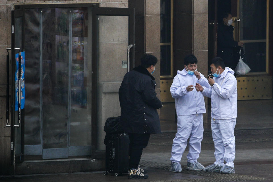 People wear protective suits as they smoke at the railway station as they arrive in Beijing, Tuesday, Feb. 11, 2020. China's daily death toll from a new virus topped 100 for the first time and pushed the total past 1,000 dead, authorities said Tuesday after leader Xi Jinping visited a health center to rally public morale amid little sign the contagion is abating. (AP Photo/Andy Wong)