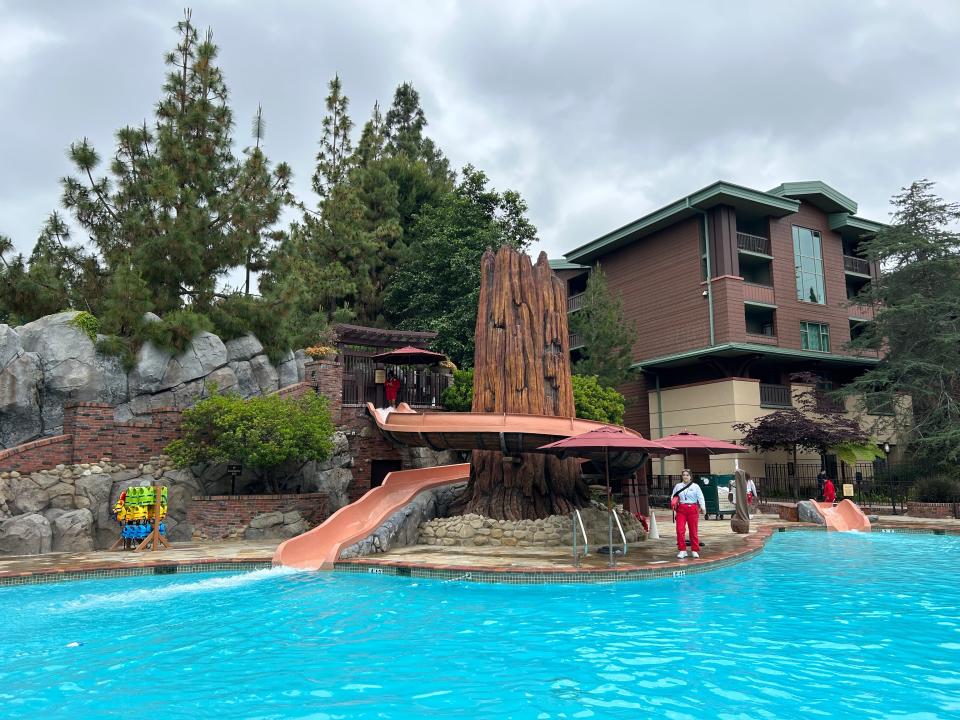 A pool with two waterslides and a lifeguard.