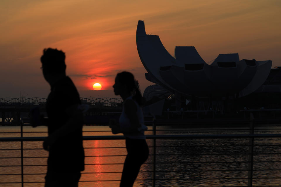 People jog along the Jubilee Bridge as the sun rises behind the ArtScience Museum at Marina Bay on February 15, 2021 in Singapore.  (Photo by Suhaimi Abdullah/NurPhoto via Getty Images)