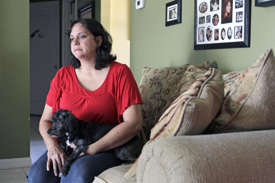 In this Tuesday, July 31, 2012 photo, Marisol Walker sits with her dog in her home in Ocoee, Fla. Walker is fighting to keep the home that she and he husband bought about a year before his business collapsed. Walker says they haven't been able to pay the mortgage in 1½ years. She works part-time, while her husband is trying to restart his business. She finds the current political debate alienating. "I listen to politicians today and it makes me angry," she says. "I want them to explain to me how two willing workers are struggling and have lost everything. ... I don't think it matters who's running the government. I don't see how any of them are going to help any of us living in the real world." (AP Photo/John Raoux)