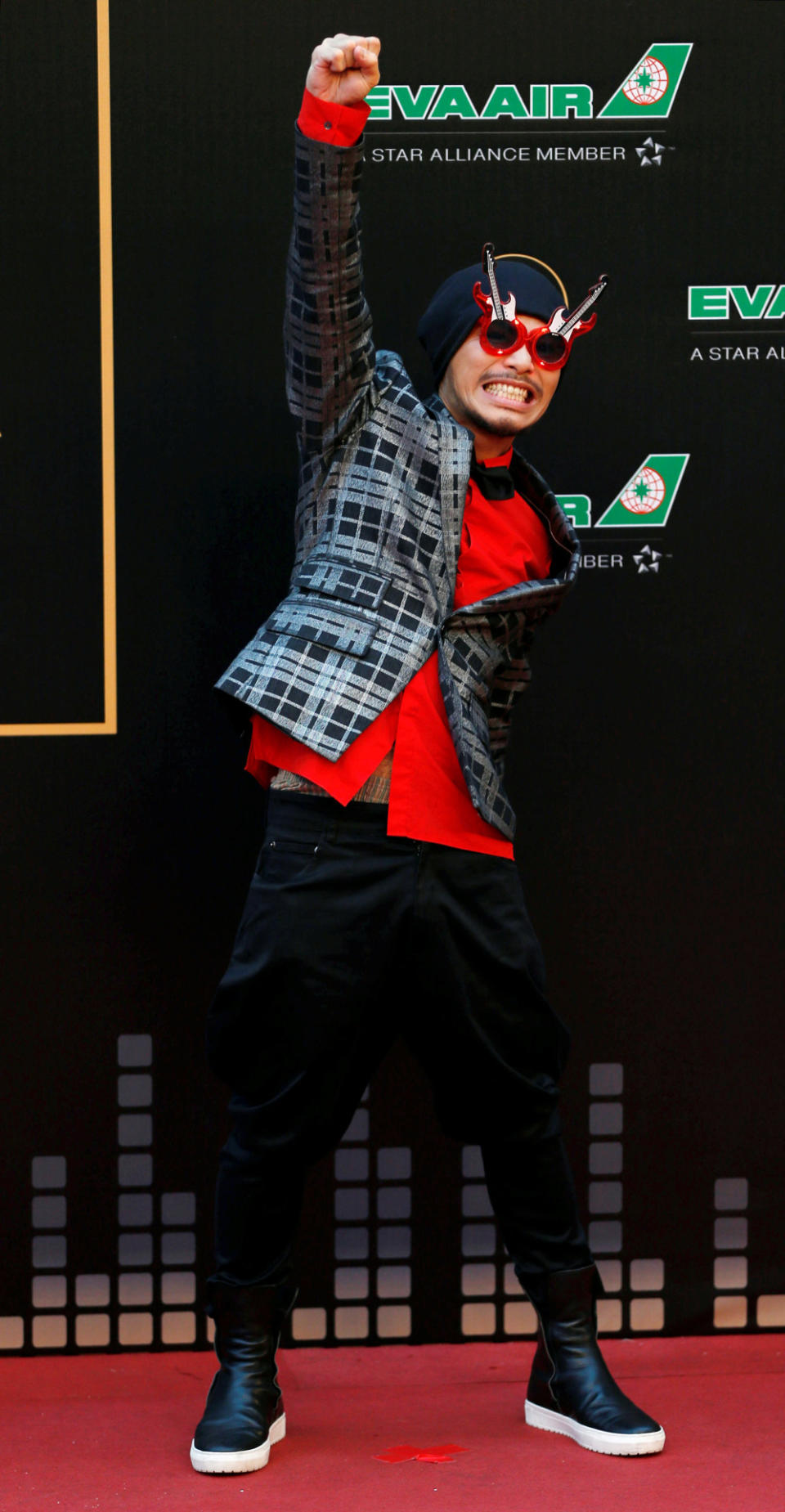 Malaysian singer Wee Meng Chee, also known as Namewee, poses on the red carpet with a checked jacket, red shirt and black pants, which are paired with guitar sunglasses. (Reuters/Tyrone Siu)