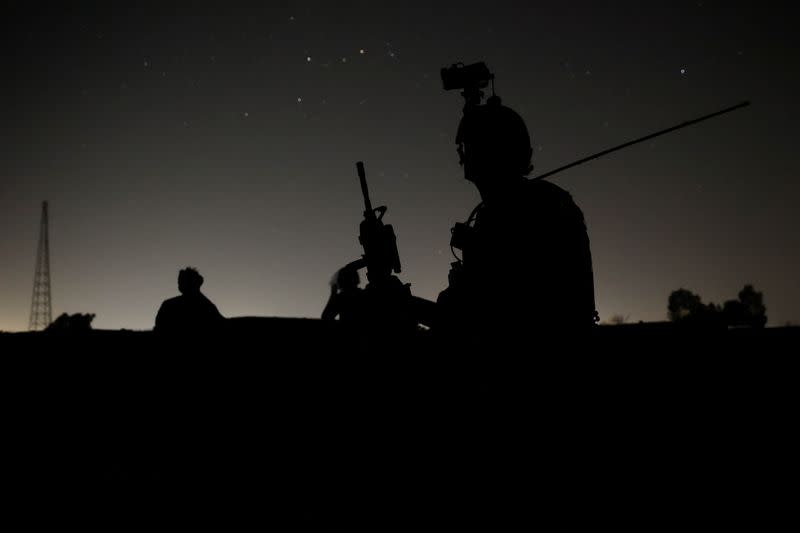 Members of the Afghan Special Forces keep a watch as others search houses in a village during a combat mission against Taliban, in Kandahar province