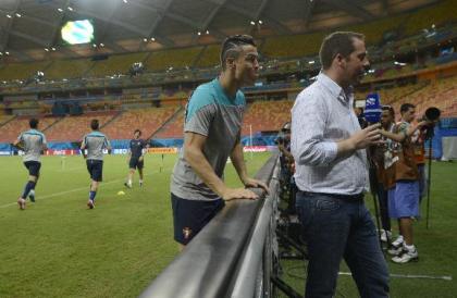 Portugal's Cristiano Ronaldo (L) jokes behind RTP television journalist Hugo Gilberto. (AP Photo)