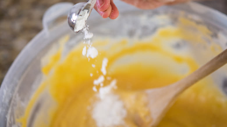 Baking powder falling into a bowl of cake batter