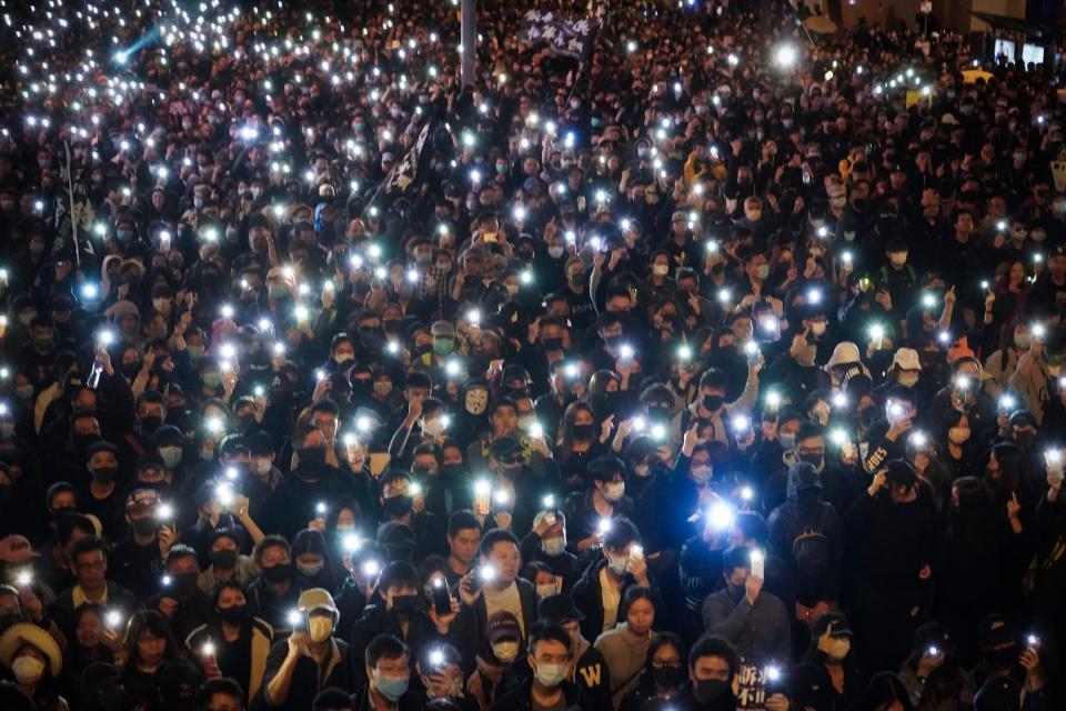 Protesters hold up their phone lights (AP)