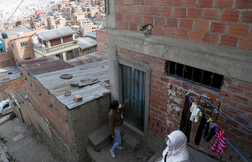 In this May 13, 2020 photo, “Adopt a Grandparent" volunteer Carolina Arraya knocks on the door of her "adopted" grandmother, in La Paz, Bolivia. Some Bolivians are adopting grandparents to make life a little easier for those most vulnerable to the new coronavirus pandemic. (AP Photo/Juan Karita)