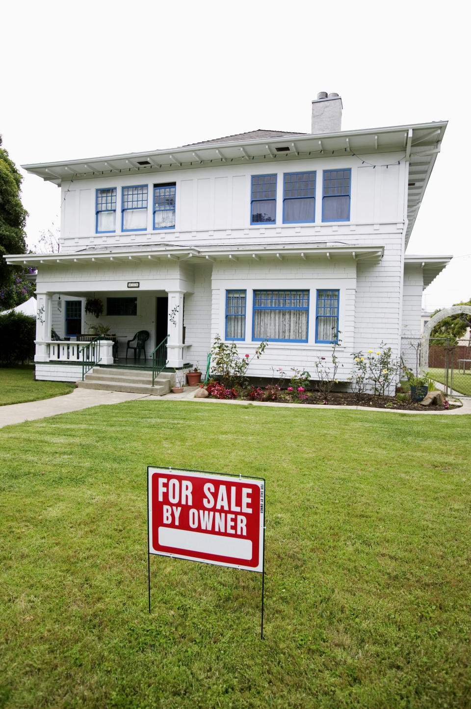 Two-story house with a "For Sale By Owner" sign on the front lawn