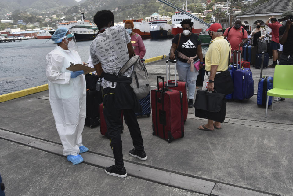 British, Canadian and U.S. nationals wait to board the Royal Caribbean cruise ship Reflection to be evacuated free of charge, in Kingstown on the eastern Caribbean island of St. Vincent, Friday, April 16, 2021. La Soufriere volcano has shot out another explosive burst of gas and ash Friday morning as the cruise ship arrived to evacuate some of the foreigners who had been stuck on a St. Vincent island by a week of violent eruptions. (AP Photo/Orvil Samuel)