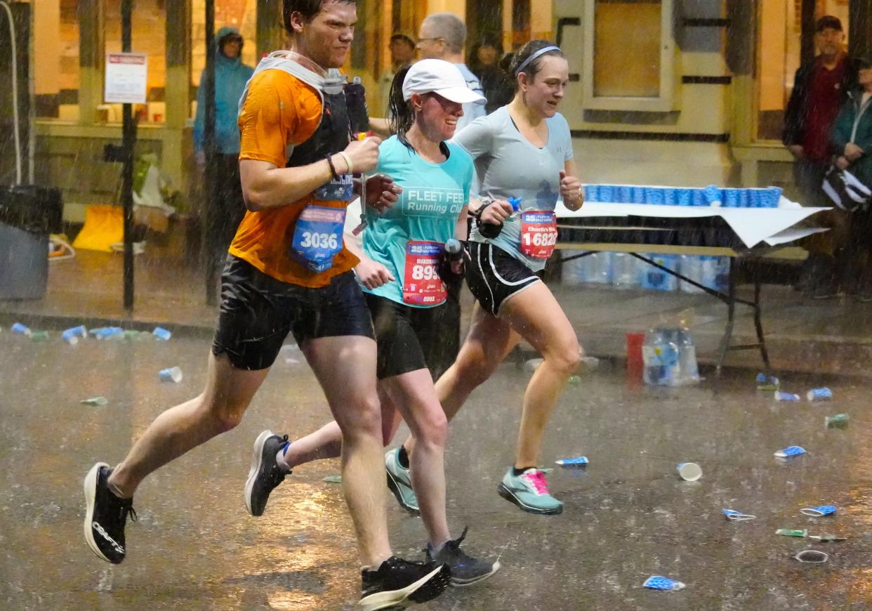 Runners make their way across Seventh Street in downtown Cincinnati, just shy of the five mile marker during the Cincinnati Flying Pig Marathon on Sunday. About this time, as heavy rain fell, along with thunder and lightning, members of the bike support yelled, "The race is paused. Shelter in place."