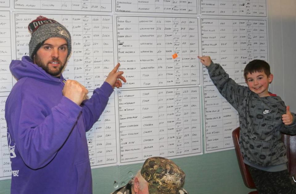 First place winner Dustin Andreis, left, and his son and hunting buddy Zyler point to Dustin’s winning coyote on the wall at Mosquito Creek.