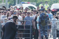 People gather to lay flowers near a school after a shooting on Tuesday in Kazan, Russia, Wednesday, May 12, 2021. Russian officials say a gunman attacked a school in the city of Kazan and Russian officials say several people have been killed. Officials said the dead in Tuesday's shooting include students, a teacher and a school worker. Authorities also say over 20 others have been hospitalised with wounds. (AP Photo/Dmitri Lovetsky)