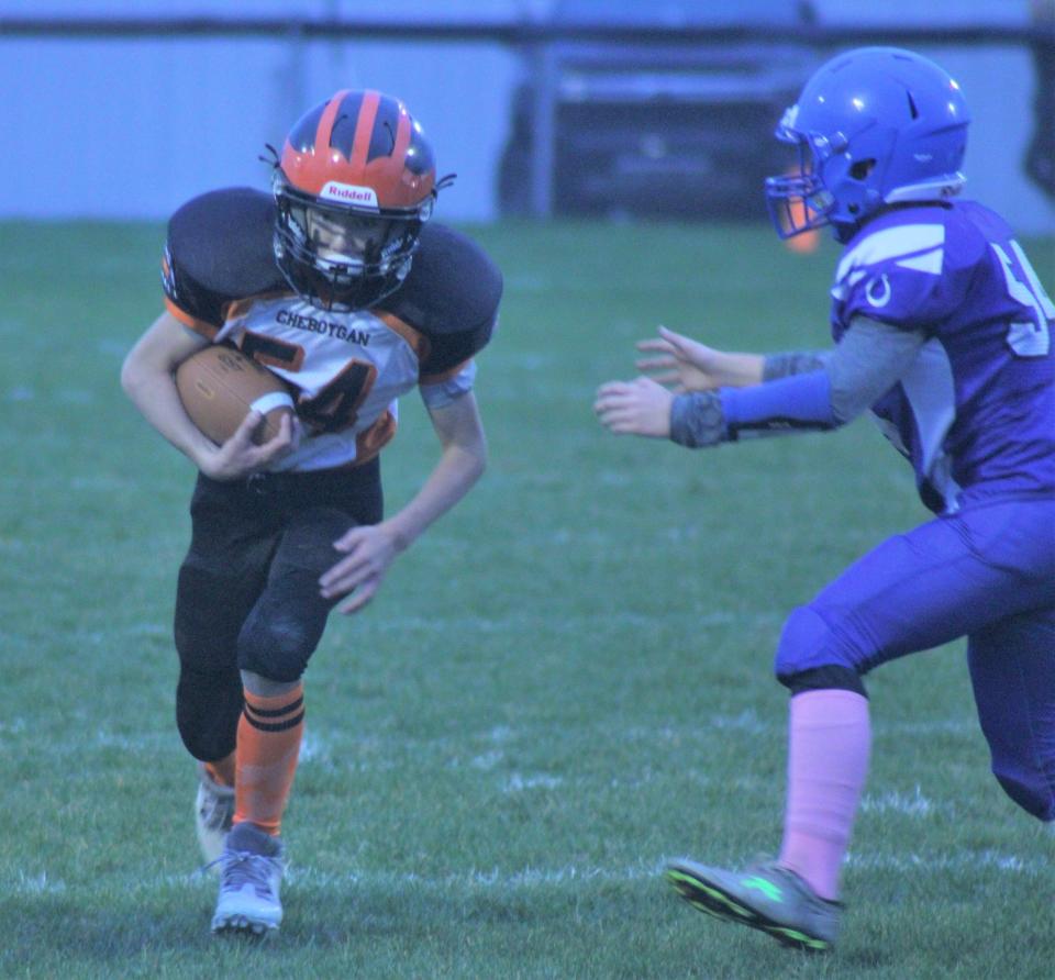 Reid Schryer (left) runs for positive yardage during the Cheboygan Junior Chiefs 5th/6th grade football team's Super Bowl matchup against the Oscoda Colts at Western Avenue Field on Saturday night.