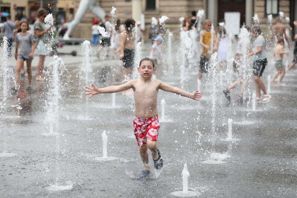 A child runs through a fountain.