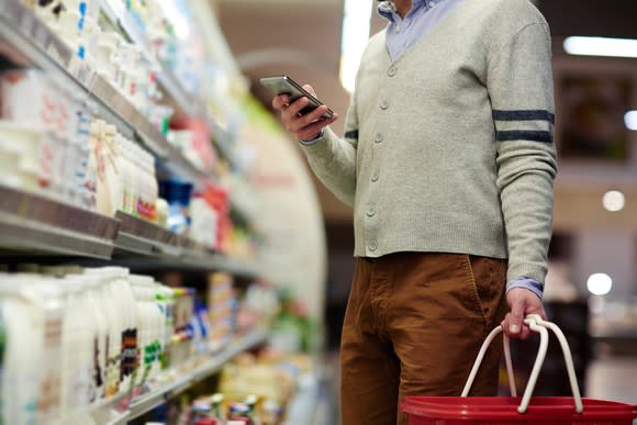 Shopper in a grocery store looking at his phone.