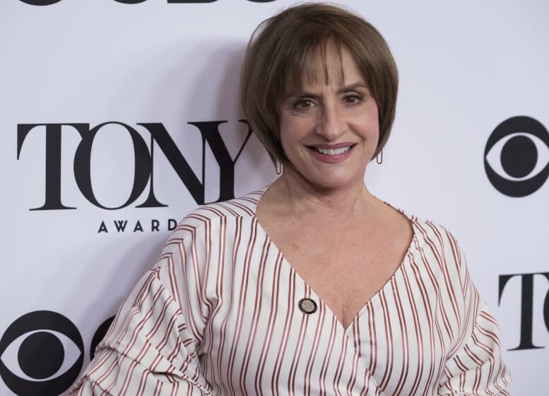 A woman with short hair smiles at a red-carpet event