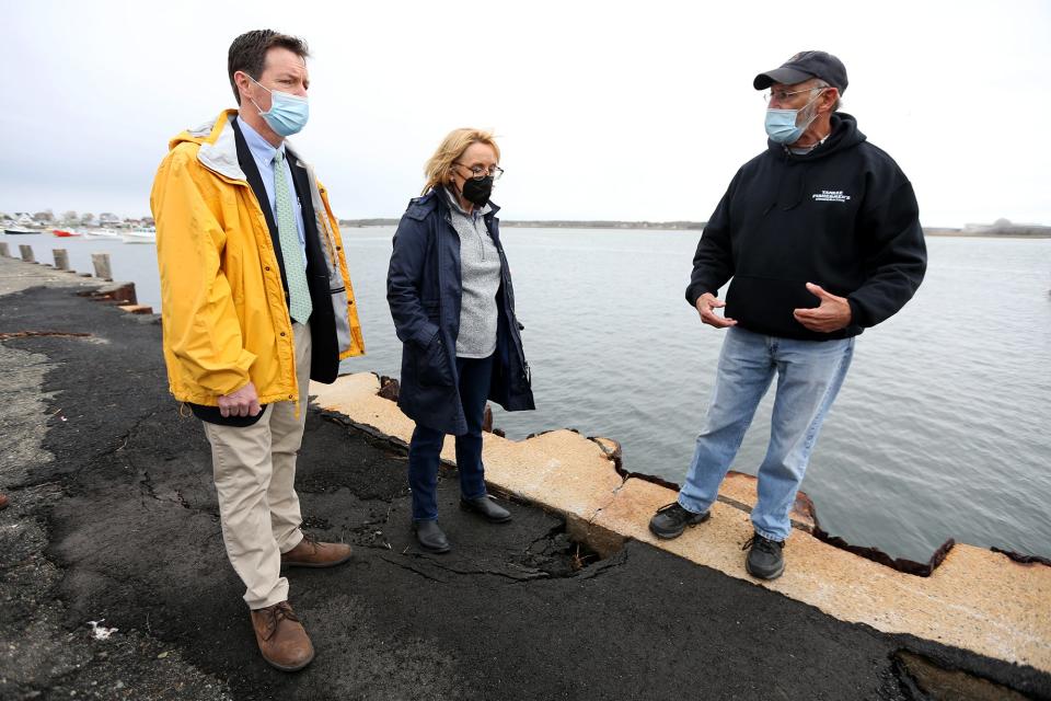 From left, state Sen. Tom Sherman and U.S. Sen. Maggie Hassan stand on the uneven pavement at the docks as Jim Titone, the president of the Yankee Fishermen’s Cooperative, advocates for repairs. 