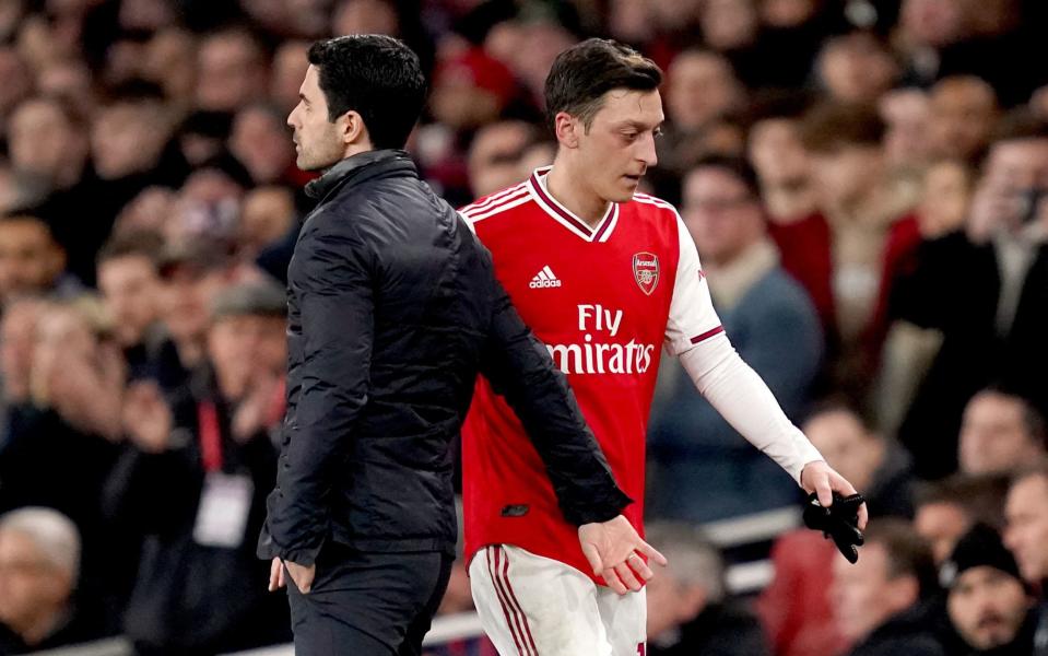 Mesut Ozil walks past Mikel Arteta - PA