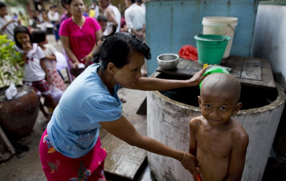 In this April 8, 2014 photo, a mother bathes a boy just after his head has been clean-shaven during an ordination ceremony at a Buddhist monastery in suburbs of Yangon, Myanmar. Though most boys only remain monks for a few days, ordination is seen as a right of passage in this predominantly Buddhist nation of 60 million. In addition to learning the basic tenants of their faith, it serves as a sort of spiritual credit for their parents, helping emancipate them from a viscous cycle of rebirth and death. (AP Photo/Gemunu Amarasinghe)