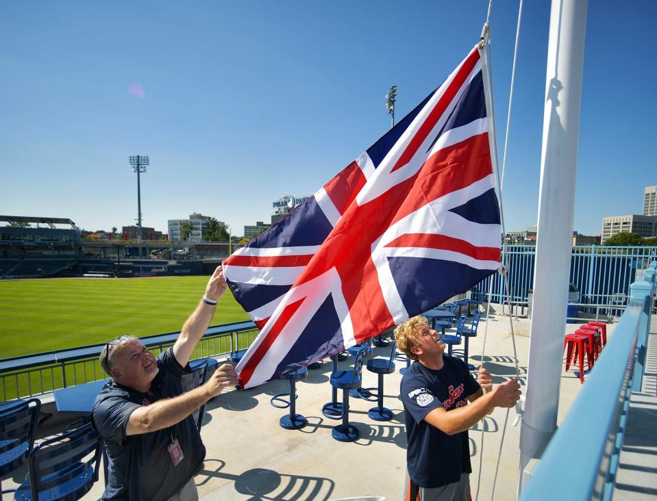 Jeff Caster, left, and Zach Johnson raise the flag of the United Kingdom over Polar Park in Worcester to commemorate the death Thursday of Queen Elizabeth II.