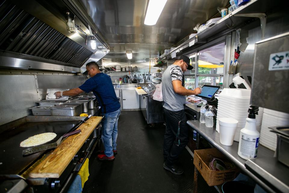 Andres Mendez, left, makes tacos, while Carlos Martinez, right, takes a customerÕs order in the Chile & ChiliÕs Taqueria food truck on Tennessee Street on Wednesday, May 31, 2023. 